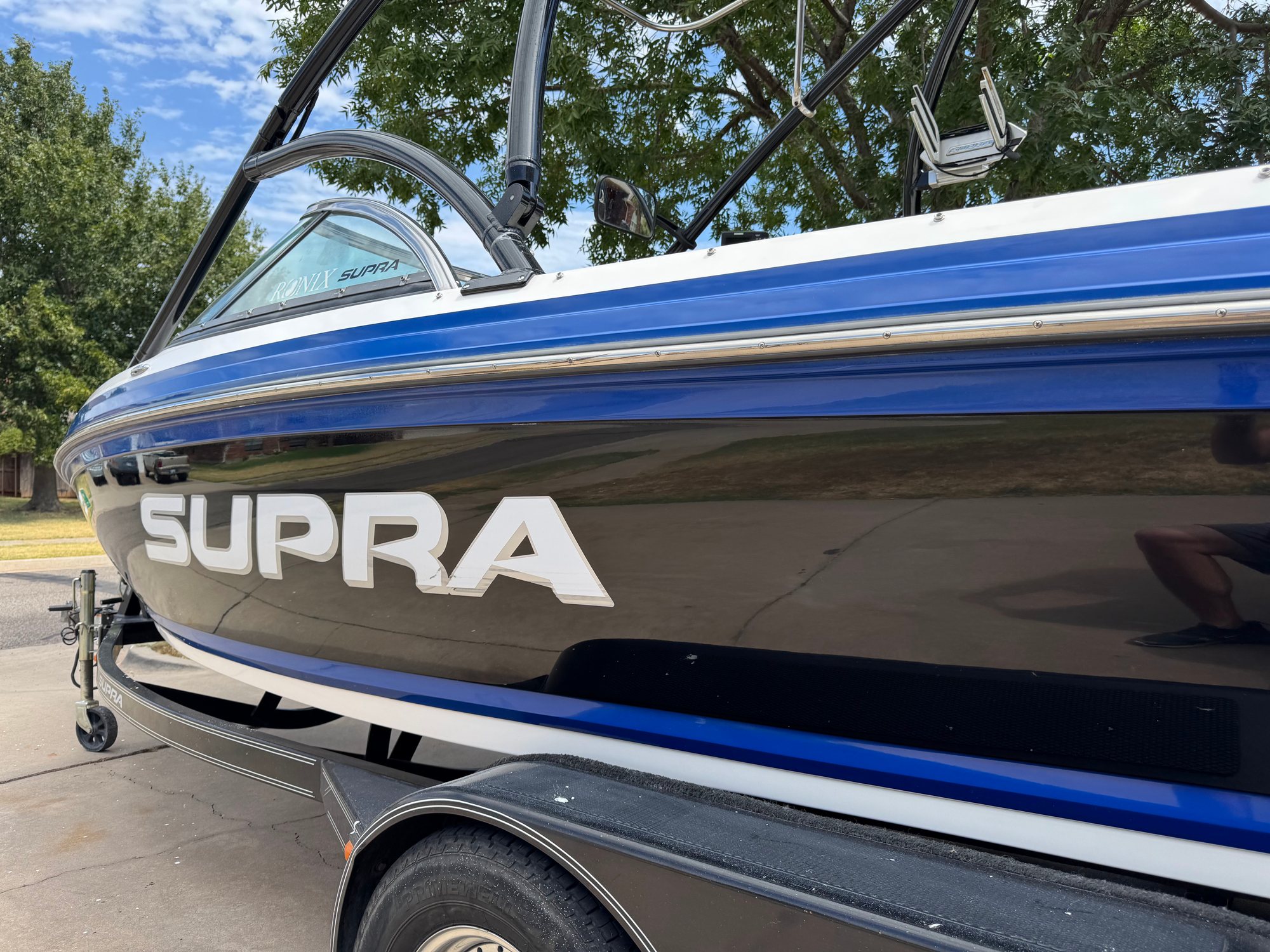 After: the Supra's black hull polished to a mirror, SUPRA lettering and tower reflected in the gelcoat