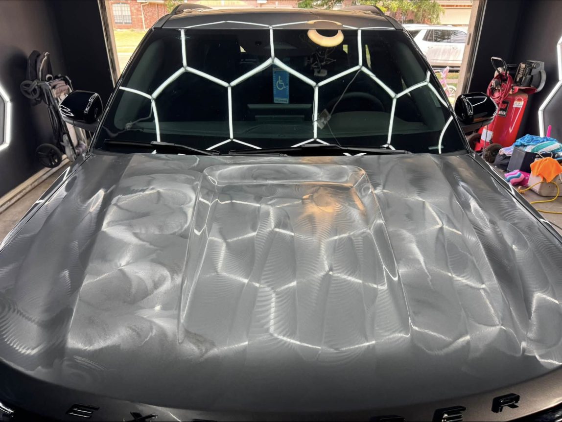 Explorer hood before correction: swirl marks and holograms visible under hex lights