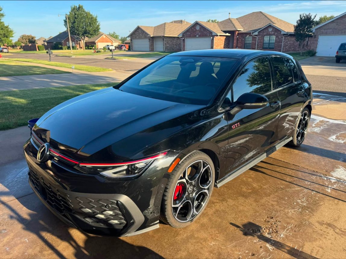 Black VW GTI, freshly detailed, in a driveway at sunset